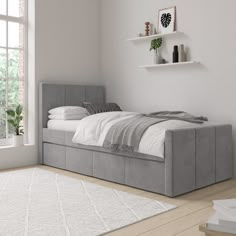 a bed sitting on top of a wooden floor next to a white rug and window