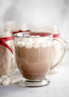 two mugs filled with hot chocolate and marshmallows on a white table