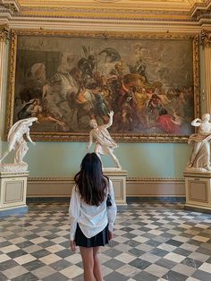 a woman standing in front of a large painting