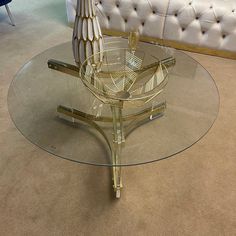 a glass coffee table with gold accents on top and a white couch in the background