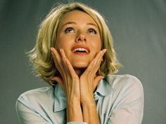 a woman is posing with her hands on her face and looking up to the sky