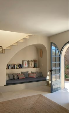 a living room filled with furniture next to an open door and staircase leading up to the second floor