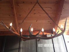 a deer antler chandelier with five candles hanging from it's side