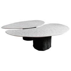 two circular tables with black bases on each side and one white table in the middle