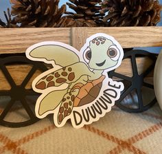 a turtle sticker sitting on top of a table next to some pineconis