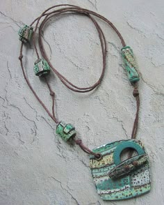 an old necklace with some beads attached to it on a stone wall, hanging from a cord