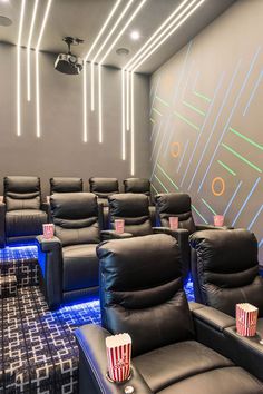 an empty movie theater with black leather recliners and popcorn buckets on the seats