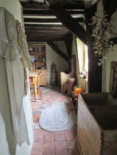 an old fashioned kitchen with brick floors and exposed beams in the ceiling, along with wooden furniture