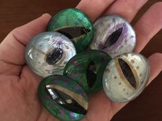 a hand holding five glass marbles in it's palm, some with different designs on them