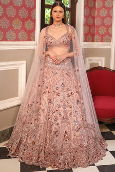 Featuring a pink lehenga in net base with embellishments. It is paired with an embroidered blouse and a net embroidered dupatta. Accessorize with statement jewellery and an elegant hairstyle for wedding, receptions, or engagement ceremonies. #Perniaspopupshop #womenswear #ethnic #whatiworewastrending #ppuslove #lehengaset #prewedding #net #stoneembroidery #threadwork #weddingwear #engagement #sangeet #embroideredlehenga #bridallook #colouroftheyearpeach Lengha Choli