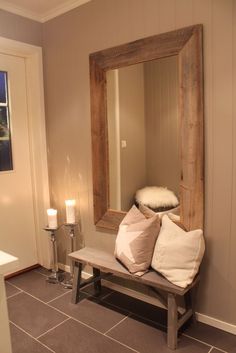 a wooden bench sitting in front of a mirror on top of a wall next to a candle