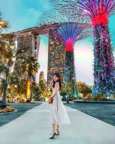 a woman standing in front of some very tall buildings with lights on it's sides