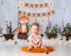 a baby is sitting on the floor in front of a birthday banner and pine cones