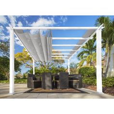 an outdoor dining area with table and chairs under a white pergolan canopy over the patio