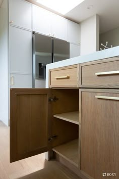 an open cabinet door in a kitchen next to a counter top and cabinets with drawers