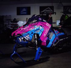 a pink and blue snowmobile parked in a garage