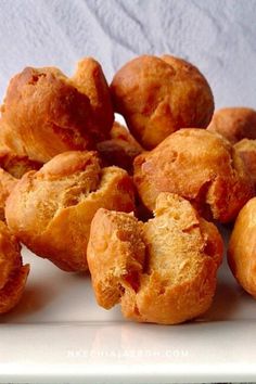 a pile of doughnuts sitting on top of a white plate