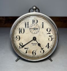 an old clock is sitting on the floor with numbers and hands in front of it