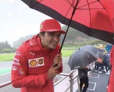 a man holding an umbrella on top of a race track with other people behind him