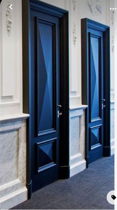 two blue doors are next to each other in a room with white and black walls