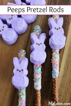 some bunny shaped candy sticks on top of a wooden table with sprinkles