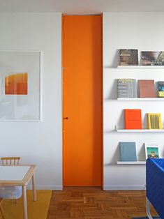 an orange door in a white room with bookshelves