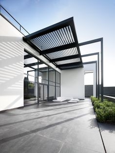 an empty building with lots of windows and plants on the outside wall, under a pergolated roof