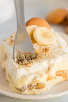 a fork is stuck into a dessert on a plate with bananas and other fruit in the background