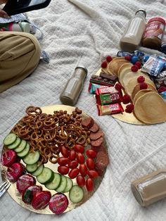 a plate with pretzels, tomatoes, cucumbers and other snacks on it