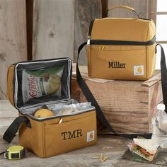 two cooler bags sitting next to each other on top of a wooden table with food in it