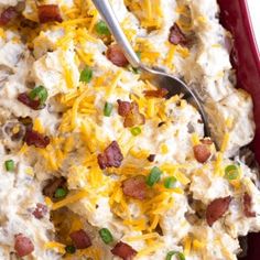 a red casserole dish filled with mashed potatoes and bacon