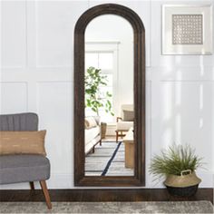 a large mirror sitting on top of a wooden floor next to a chair and potted plant