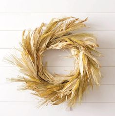 a dried wheat wreath hanging on the wall next to a white wooden planked wall