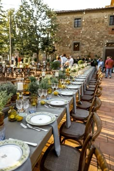 a long table is set with plates and place settings for an outdoor dinner or party