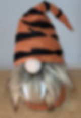 a stuffed animal wearing a striped hat on top of a wooden table next to a wall