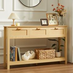 a wooden table with two drawers and a basket on it next to a wall mirror