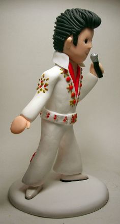 a figurine of a man holding a microphone in his right hand and wearing a white outfit