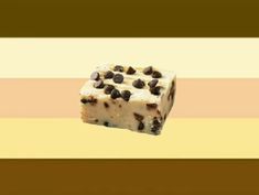 a piece of cake with chocolate chips on it sitting in front of a striped wall