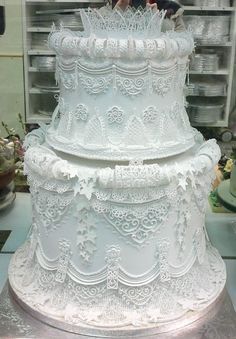 a three tiered white cake sitting on top of a metal tray in front of a glass case