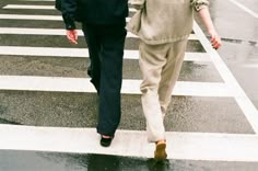 two people walking across a street in the rain