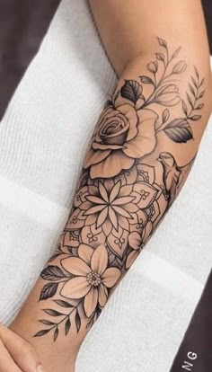 a woman's arm with flowers and leaves on it