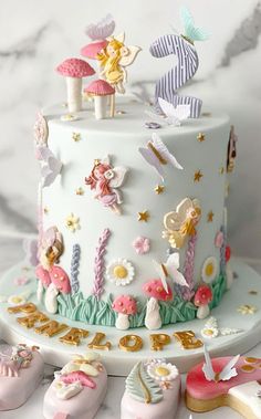 there is a cake decorated with little fairy figurines