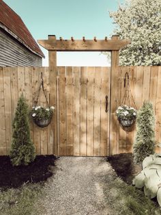 a wooden gate with two hanging planters on it