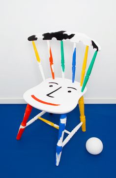 a white chair sitting on top of a blue floor next to an orange and yellow ball