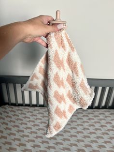 a hand holding a towel over a crib in a room with patterned flooring