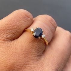 a woman's hand with a ring on it that has an oval shaped blue sapphire and two white diamonds