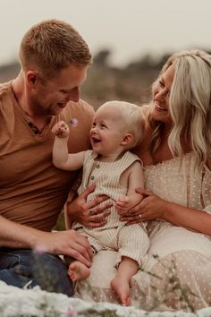 a man and woman holding a baby in their lap