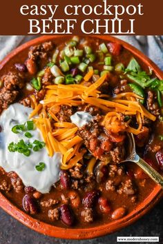 an orange bowl filled with chili and cheese