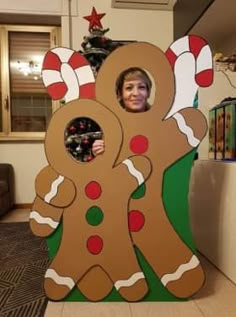 a woman standing in front of a cardboard gingerbread cutout with candy canes