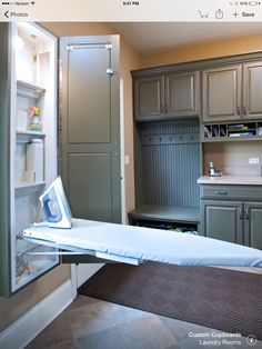 an ironing board in the middle of a kitchen with cabinets and cupboards behind it